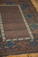 Aubergine boteh field and indigo gul motifs on the antique Belouch rug's worn main border.