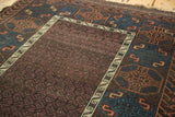 Hand-knotted antique Belouch rug close-up: aubergine field, ivory wave, and terracotta geometric border.