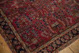 Vintage American Sarouk rug corner, burgundy field, navy floral border, worn fringed edge.