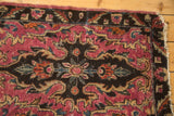 Corner detail of antique Lilihan rug, showing fuchsia field, rococo floral pattern, and tattered fringe.