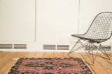 Antique Lilihan rug mat with dramatic fuchsia medallion on dark ground, showing tattered ends.