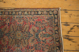 Antique Lilihan rug corner with faded raspberry field, navy floral border, scrolling vinery, and fabric-capped edge.