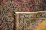 Antique Lilihan rug corner shows faded raspberry, navy florals, tight hand-knotted weave, and secured end.