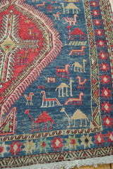 Pomegranate red medallion, navy field, and stylized camel motifs on a Soumac runner.