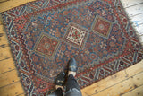 A top-down view of the antique Qashqai rug, illustrating the scale of its triple diamond medallions and geometric field.