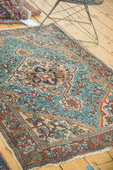 Angled view of vintage Persian Lilihan rug, oversize aqua and blush floral medallion.