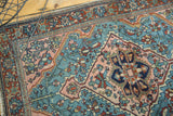 Corner detail of a vintage Persian Lilihan rug with aqua, blush, and wine floral motifs.