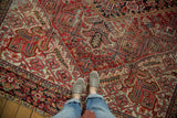 Vintage Heriz carpet section featuring brick red, ivory, blue serrated leaves, and visible wear.