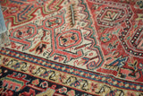 Vintage Heriz carpet showing geometric field and border details with brick red, ivory, navy tones.