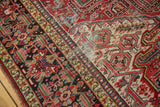Vintage Heriz carpet's intricate border detail with red, black, and ivory motifs, showing foundation wear.