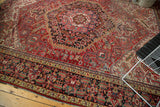 Intricate border of vintage Heriz rug, with a brick red field and navy scrolling motifs.