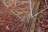 Vintage Heriz carpet's brick red field, geometric motifs, and border with even wear.
