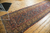 Aged tatter visible on the antique Kurdish runner's saffron yellow border and navy field.