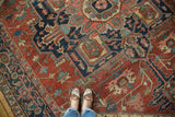 Antique Serapi carpet's geometric field with stylized floral motifs in madder red, navy, and ivory.