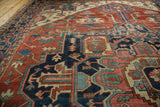 Ornate geometric tendrils and floral cross sections on a hand-knotted antique Serapi rug.