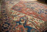 Detailed view of brick red, navy, and ivory geometric floral motifs on an antique Serapi.