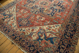 Antique Serapi carpet's navy border framing a brick red field with geometric floral tendrils.