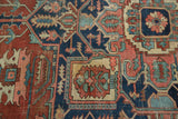 Navy, brick red, and sky blue geometric floral patterns on an antique Serapi rug.