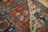 Patinaed geometric motifs on antique Serapi carpet in madder red, navy blue, and ivory.