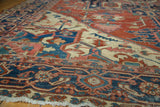 Antique Serapi carpet's navy border, geometric tendrils, brick red, ivory field, and frayed fringe.