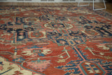 Hand-knotted Serapi rug's field shows geometric tendrils in brick red, navy, blush.