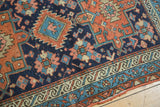Hand-knotted Karaja rug detail: geometric field patterns in navy and madder red with a teal border.