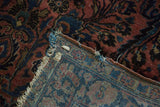 Antique American Sarouk rug corner, revealing low pile floral design and tightly woven back with frayed edges.