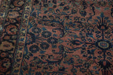 Time-softened dusty rose field with intricate navy blue and gold floral motifs on antique Sarouk rug.