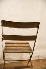 Rear view of vintage French cafe chair, showing metal backrests and weathered wood seat.