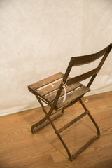 Curved metal legs and lower frame of the vintage French cafe chair with patina.