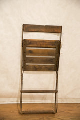 Vintage French cafe chair folded, showing wooden slats and patinated metal.
