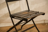 Dark wood seat slats with worn patina and metal frame of a vintage French chair.