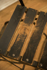 Vintage French chair seat with worn black wood slats and visible patina.