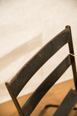 Vintage French cafe chair's dark metal backrest, showing aged patina and surface wear.