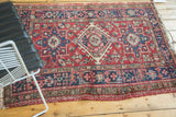 Corner of Karaja rug, showing navy border, cherry field, and light selvage tatter.