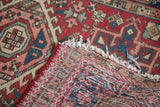 Vintage Karaja rug's hand knotted foundation, geometric cherry red pile, and tattered selvage.