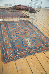 Antique Heriz rug's brick red field with sky blue geometric motifs and side tatter.