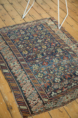 Detailed corner of an antique Caucasian rug, showing intricate blue, red geometric patterns.