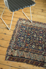Antique Caucasian rug corner, displaying intricate geometric patterns in navy, red, and ivory.