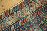 Intricate madder red, navy, and ivory patterns with worn foundation on antique Caucasian rug side.