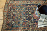 Antique Caucasian rug's intricate geometric patterns with visible wear, foundation, and tattered edge.