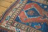 Hand-knotted vintage Caucasian rug corner with madder red, sky blue, geometric borders, intact selvage.