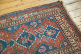 Vintage Caucasian rug corner: geometric madder red and sky blue patterns, intact selvage, tattered end.