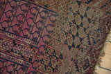 Section of hand-knotted antique Turkmen rug, geometric motifs in raspberry, madder root red, and navy.
