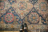 Antique Soumac carpet: blush, navy, red geometric octagonal medallions and barber pole border.