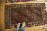 Antique Belouch rug, geometric lattice medallions on chestnut field, starburst border, natural wear.