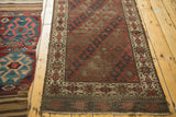 Antique Belouch rug's lower end with geometric starburst border in ivory, chestnut, and dark tones.