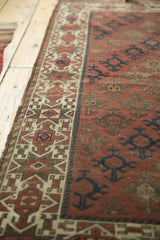 Antique Belouch rug close-up showing starburst border with ivory geometric motifs.