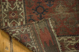Antique Belouch rug's folded corner, highlighting geometric pile, visible wear, and plain weave back.