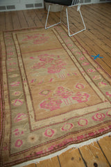 Blush pink floral motifs and ivory fringe on a vintage Turkish Oushak rug corner.